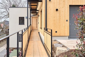 A modern building with a wooden exterior, a narrow corridor, and a small outdoor seating area. - Rosenhof with whirlpool | Grüne Tanne | seeglueck (Konstanz)