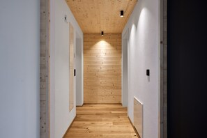 A narrow hallway with wooden panel walls and a wooden floor, leading to a dark room. - Rosenhof with whirlpool | Grüne Tanne | seeglueck (Konstanz)