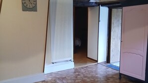 Un pasillo con suelo de baldosas, un radiador, un reloj y una puerta que da a otra habitación.