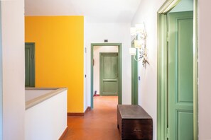 A hallway with a green door, a bench, and a wall-mounted light fixture. - Authentic Tuscan Villa Private Pool, Gym&Billiards (San Casciano val di Fesa)