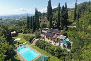 Une villa dotée d’une piscine, de panneaux solaires et offrant une vue sur le paysage environnant.