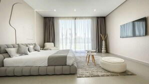 Une chambre à coucher moderne avec un grand lit, un canapé, une petite table et un vase décoratif.
