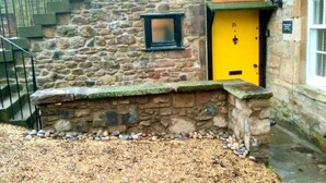 Ein Steinhaus mit einer gelben Tür und einem kleinen Fenster darüber.