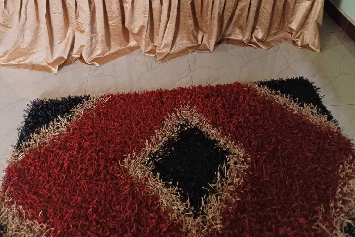 A bed with a floral bedspread, a blue blanket, and two folded towels.