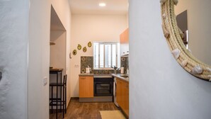 Un pasillo estrecho que conduce a una cocina con ventana, mostrador de madera y un espejo decorativo.