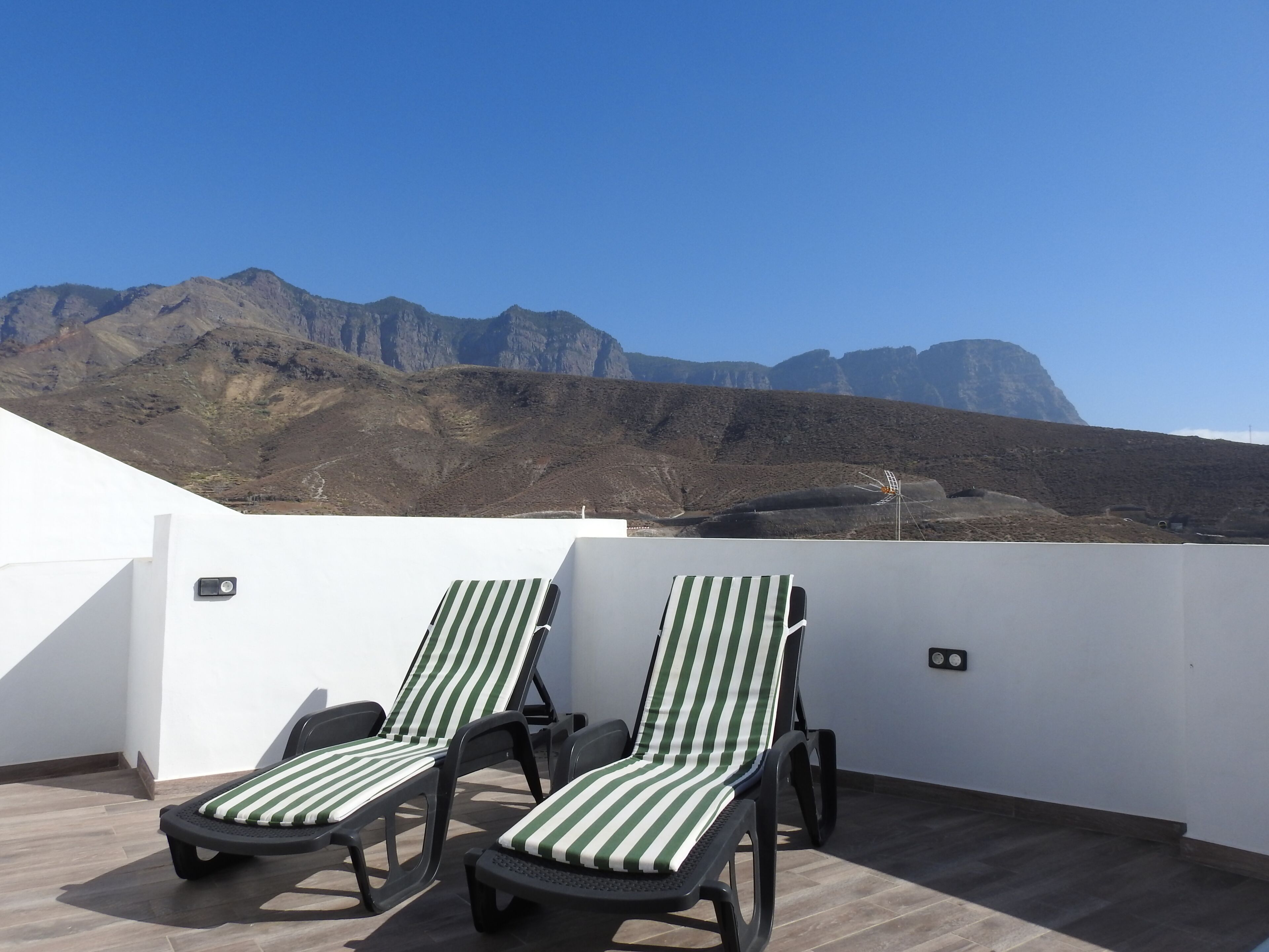 Terraza en la azotea con dos sillones de descanso y vistas a la montaña.