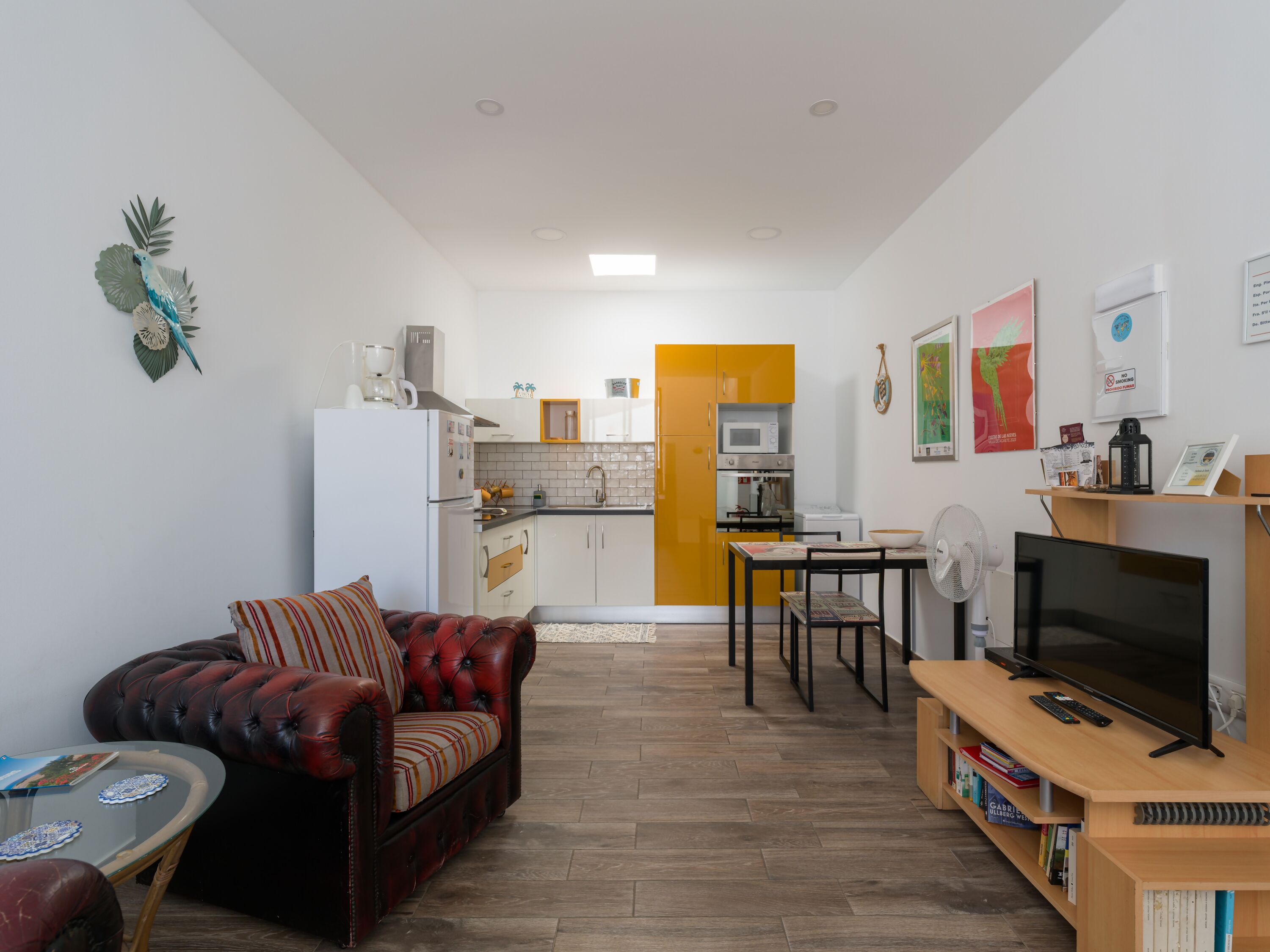 Un espacio habitable compacto con kitchenette, un sofá, una mesa de comedor y un televisor.