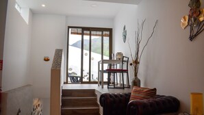 Un salon moderne avec un escalier, un coin repas comprenant une table et des chaises, et une vue sur l’extérieur.