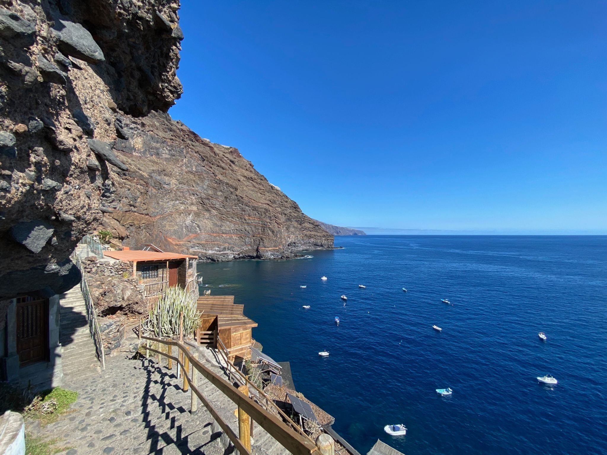 A coastal building with a stone staircase leading to a wooden deck overlooking the sea.