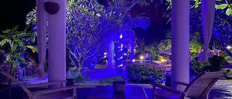 Un espacio de patio al aire libre con mesa y sillas, rodeado de plantas y un elemento decorativo de agua.