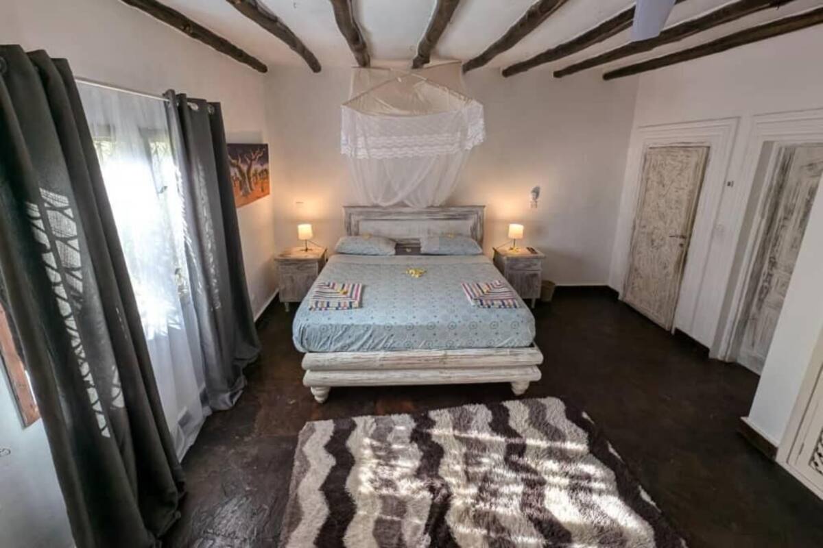 Een slaapkamer met een bed, nachtkastjes, een hemelbed en een vloerkleed.