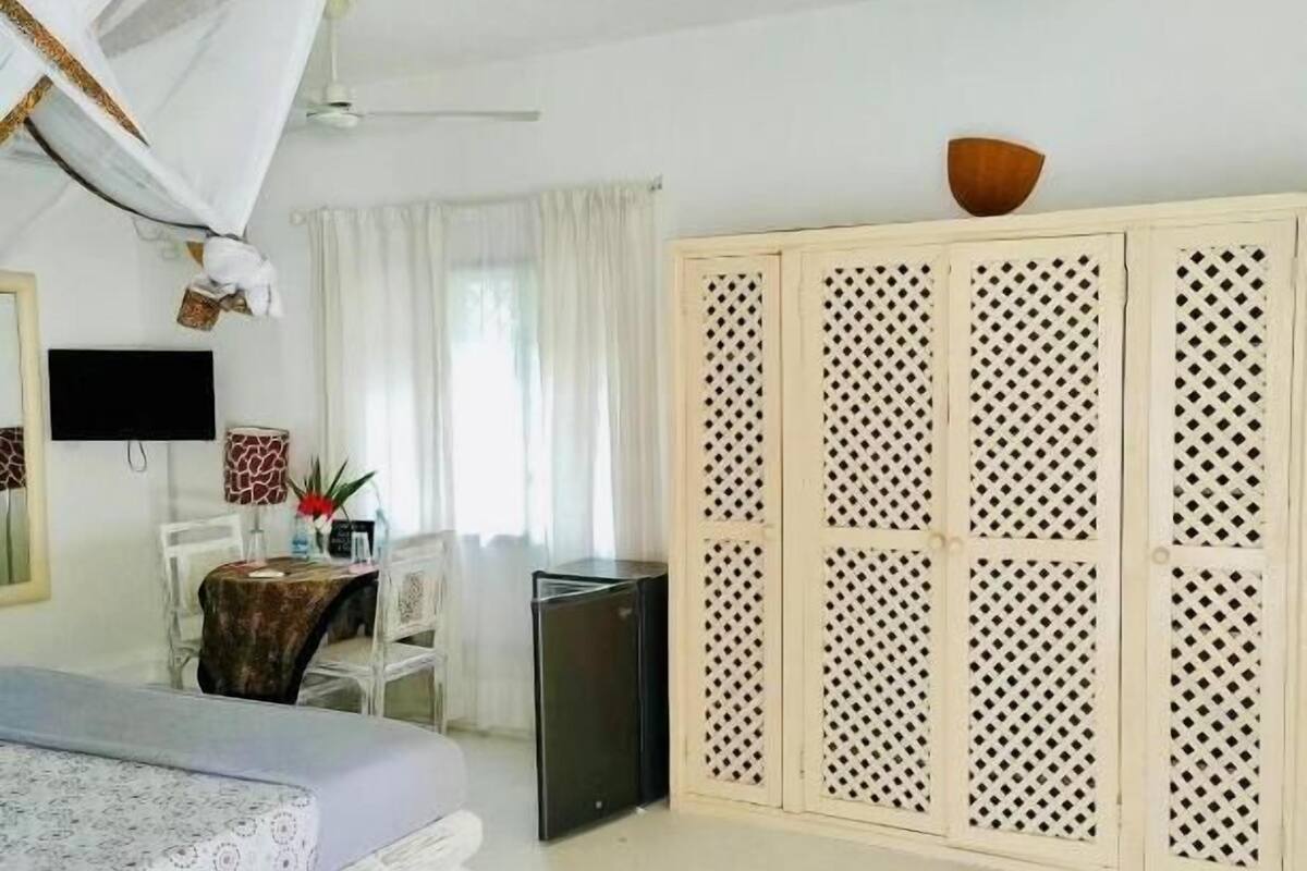 Een slaapkamer met een bed, een bureau, een stoel, een kledingkast en een kleine televisie.