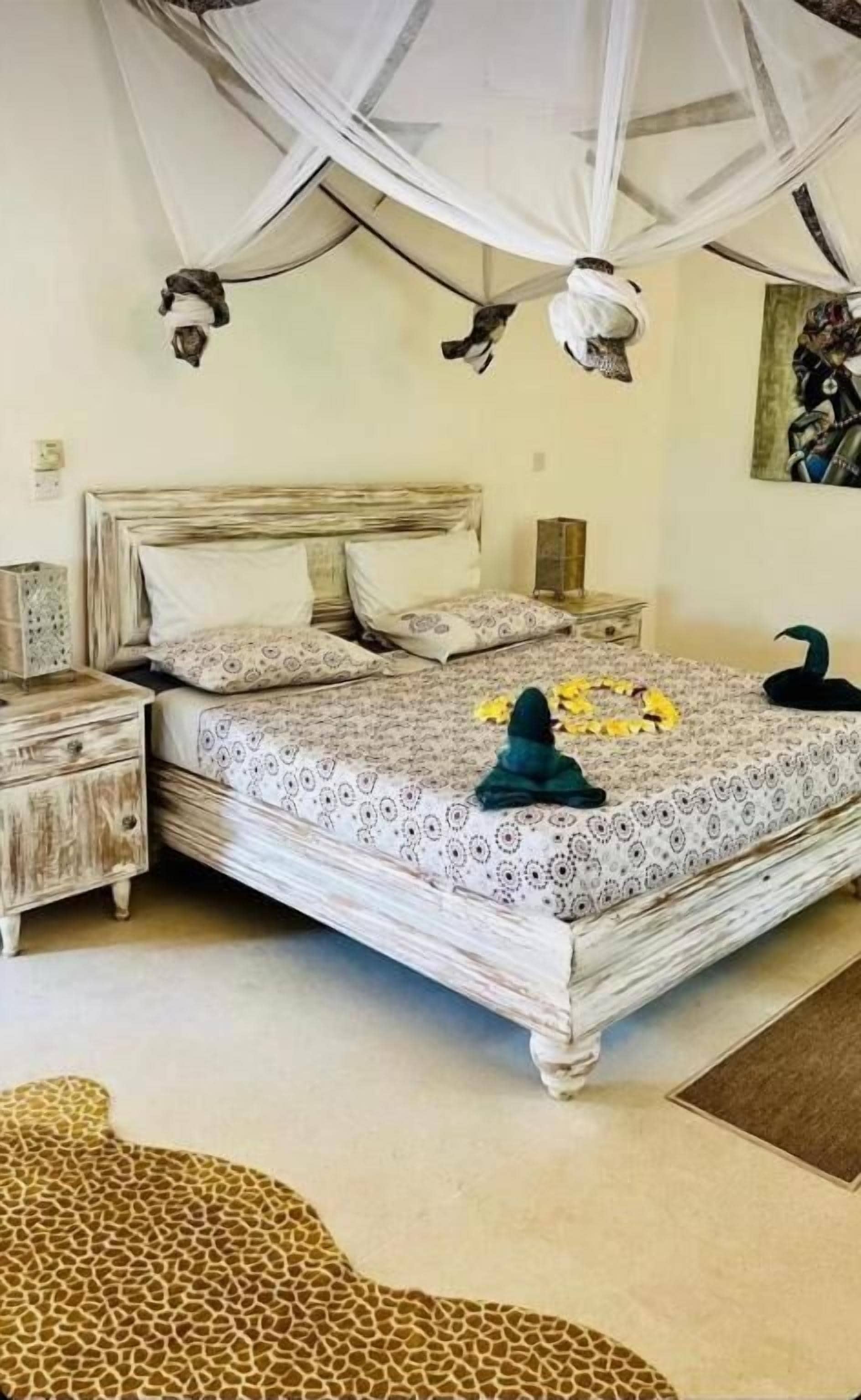 Una cama con dosel, un tapete estampado con motivos de jirafa y una decoración con forma de cisne sobre la cama.