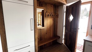 Ein Zimmer mit einem weißen Kleiderschrank, Holzregalen und einer Holztür.