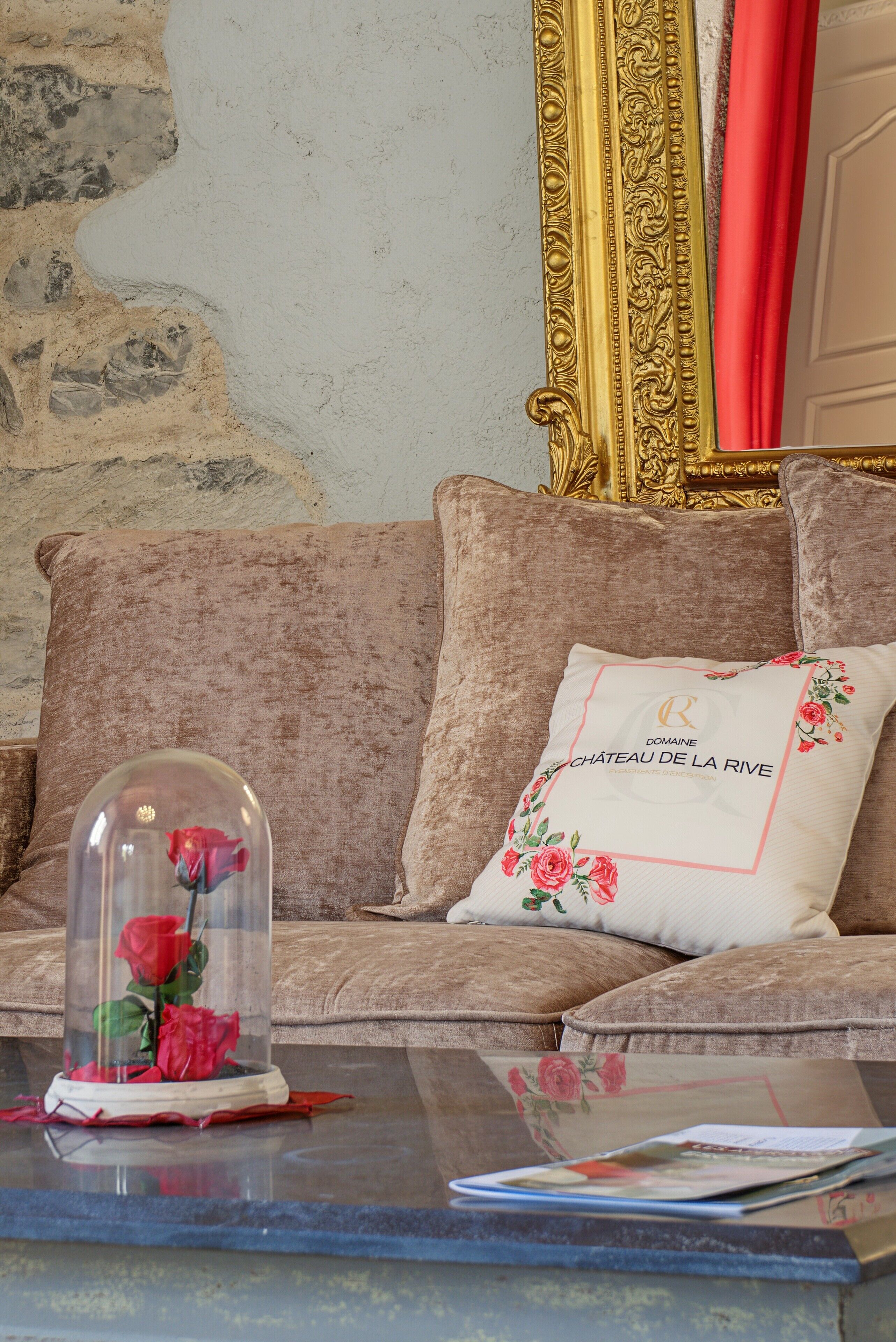 Quarto com sofá, mesa de vidro com uma rosa e almofada decorativa.