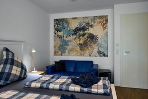 Ein Schlafzimmer mit einem Bett, einem blauen Sofa, einem Bild an der Wand und einer Tür.