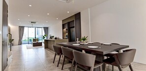 A modern dining area with a long table set for six, surrounded by six chairs. - Luxury Villa Hinai by Simple Sanctuary (George Town)