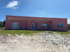 Um edifício moderno de dois andares com telhado plano, janelas amplas e um alpendre coberto com área de estar ao ar livre.