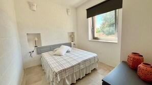 A bedroom with a bed, a window, and two wall-mounted lamps. - Recently renovated Lamia, surrounded by olive trees and Mediterranean vegetation (Ostuni)