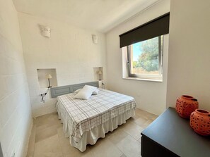 Ein Schlafzimmer mit einem Bett, zwei Wandlampen, einem Fenster mit Blick und zwei dekorativen Vasen auf einem Tisch.