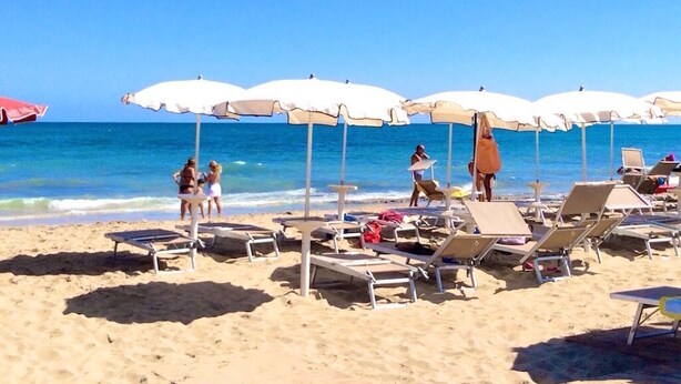 A beach with sun loungers and umbrellas, a clear blue sky, and the ocean in the background. - Recently renovated Lamia, surrounded by olive trees and Mediterranean vegetation (Ostuni)