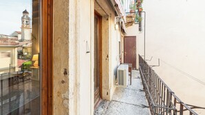 A narrow urban alleyway with a building entrance, a small outdoor seating area, and a visible air conditioning unit. - Residenza Merici - Elegante e Fiabesca (Verona)