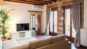A living room with a television, sofa, and potted plant. - Residenza Merici - Elegante e Fiabesca (Verona)