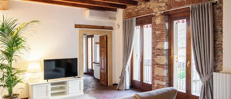 Una sala de estar con televisión, sofá y planta en maceta.