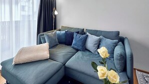 En moderne stue med en hjørnesofa, en gulvlampe og en vase med blomster.