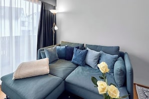 Ein modernes Wohnzimmer mit einem Ecksofa, einer Stehlampe und einer Blumenvase.