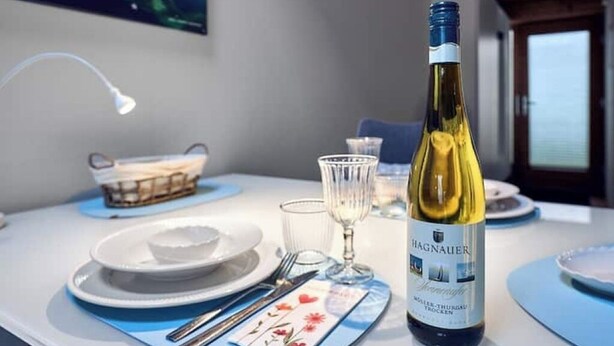 Et spisebord dækket med tallerkener, bestik, en vinflaske og glas.