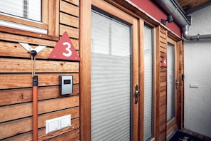 Eine Holzfassade mit einem Schild mit der Nummer 3, einer Tür und einem kleinen Stromverteiler.