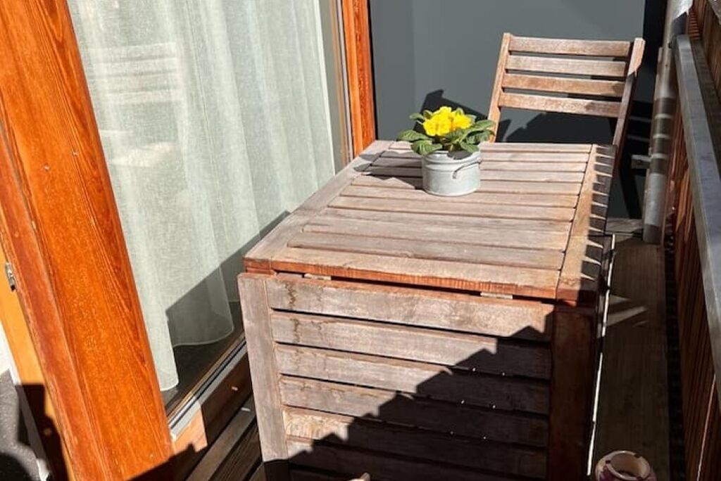 A wooden table with a potted plant on a balcony.