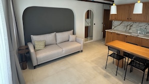 Un intérieur moderne comprenant un canapé, une table à manger et un coin cuisine.