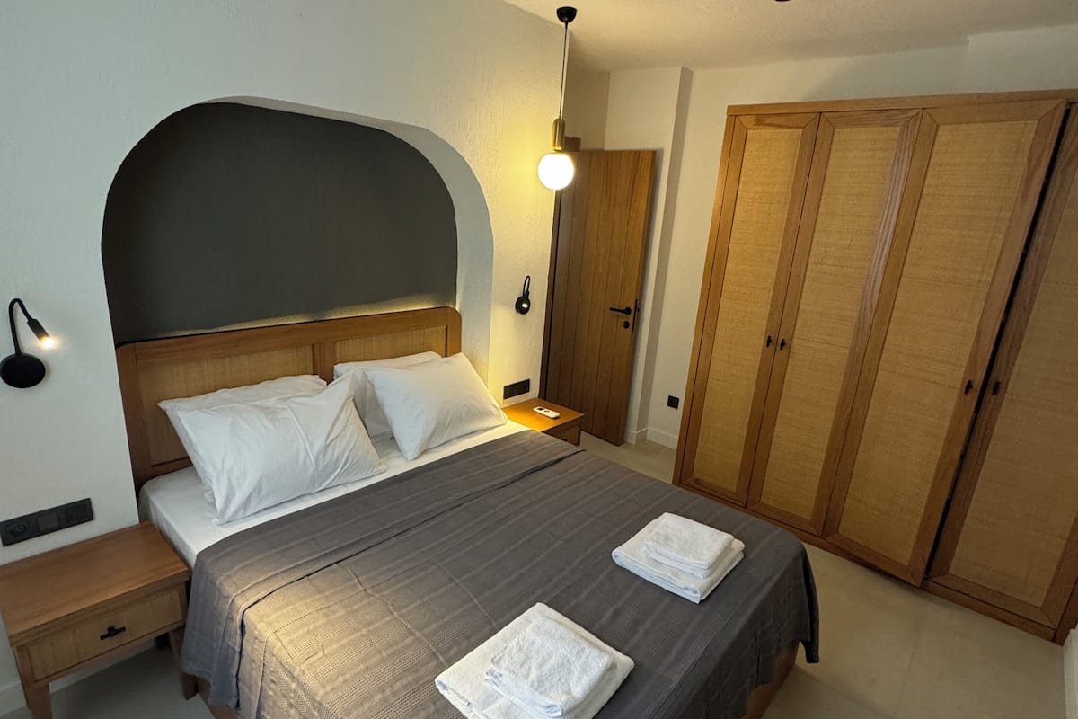 A bedroom with a bed, bedside tables, a wardrobe, and a hanging light fixture.