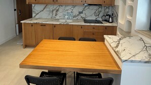 Une cuisine moderne avec des meubles en bois, un plan de travail en marbre et une table à manger en bois, accompagnée de quatre chaises.