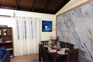 Un coin repas agrĂ©mentĂ© dâun mur en marbre, dâun tableau et dâune table dressĂ©e pour quatre personnes.