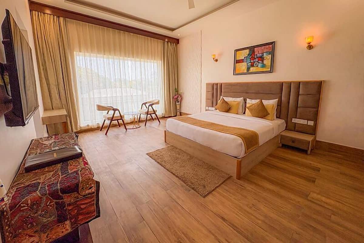 A hotel room with a bed, a desk, a chair, a ceiling fan, and a large window with curtains.