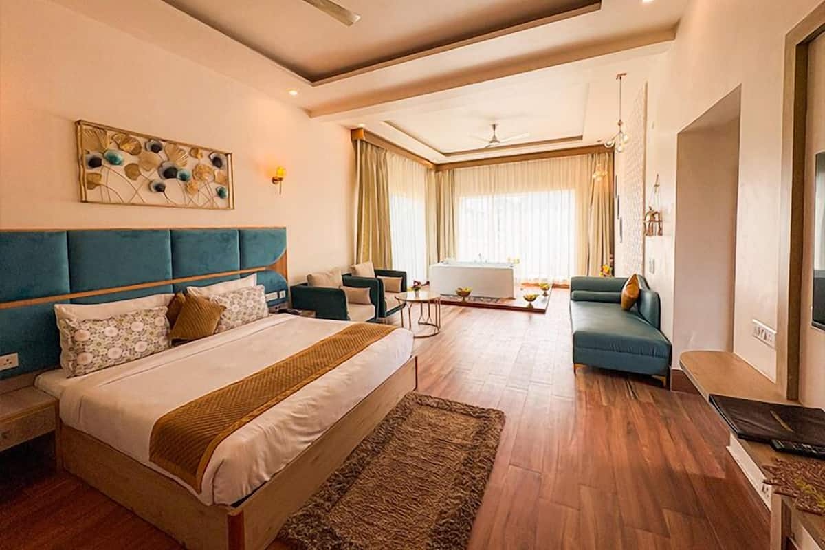 A hotel room with a bed, a sofa, a desk, and a dining area.