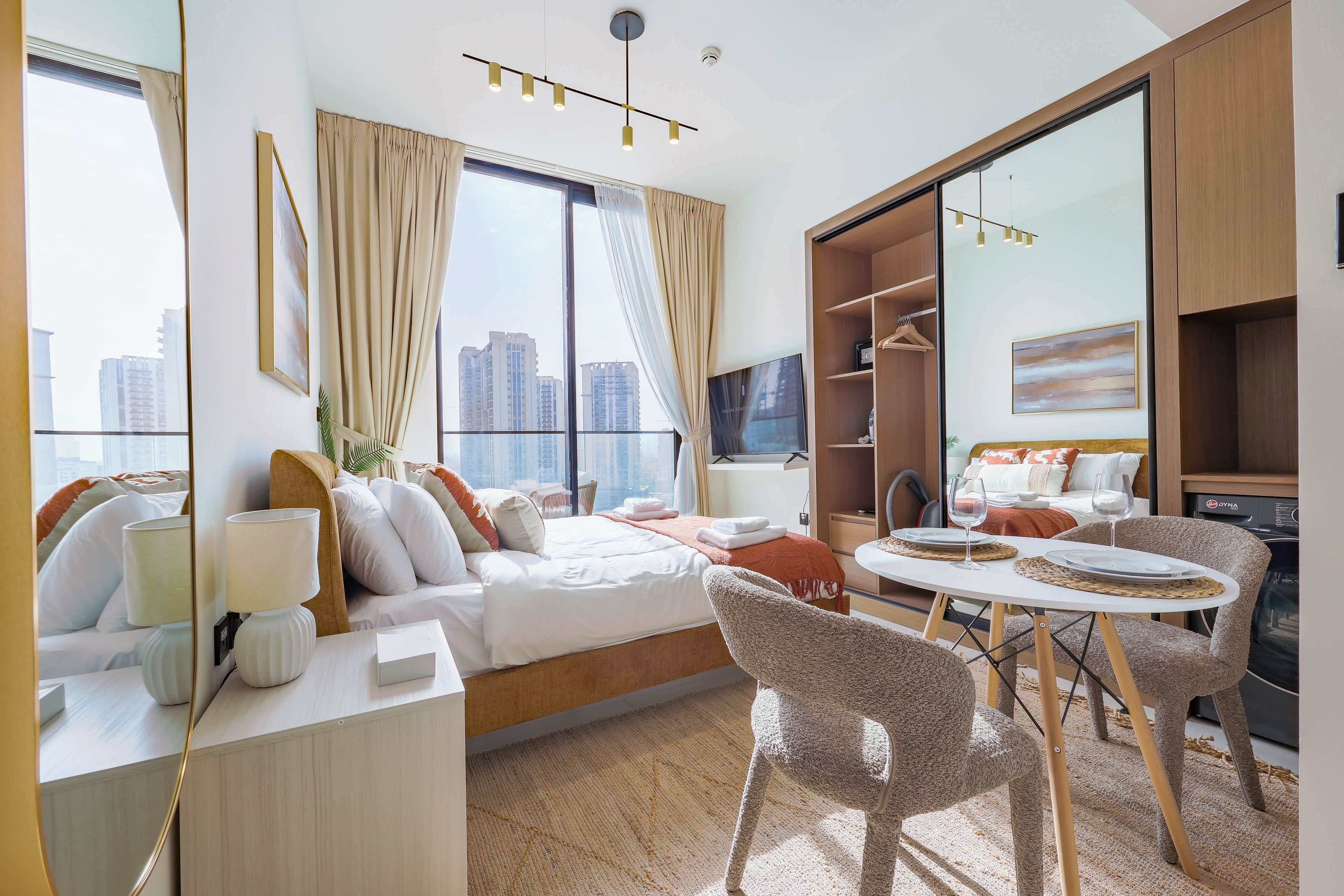 A hotel room with a bed, a desk, a chair, a dining table, and a wardrobe.