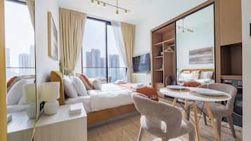 A hotel room with a bed, a desk, a chair, a dining table, and a wardrobe.