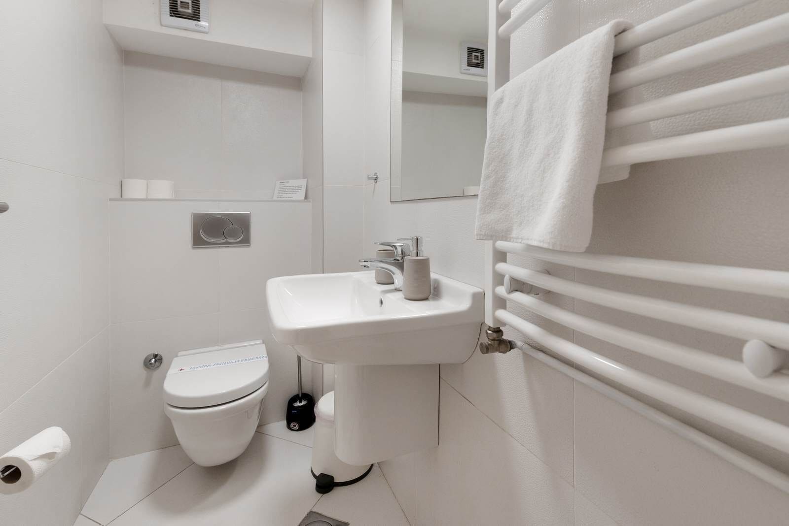 A modern bathroom with a white sink, toilet, and towel rack.