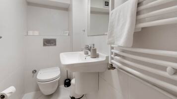 A modern bathroom with a white sink, toilet, and towel rack.