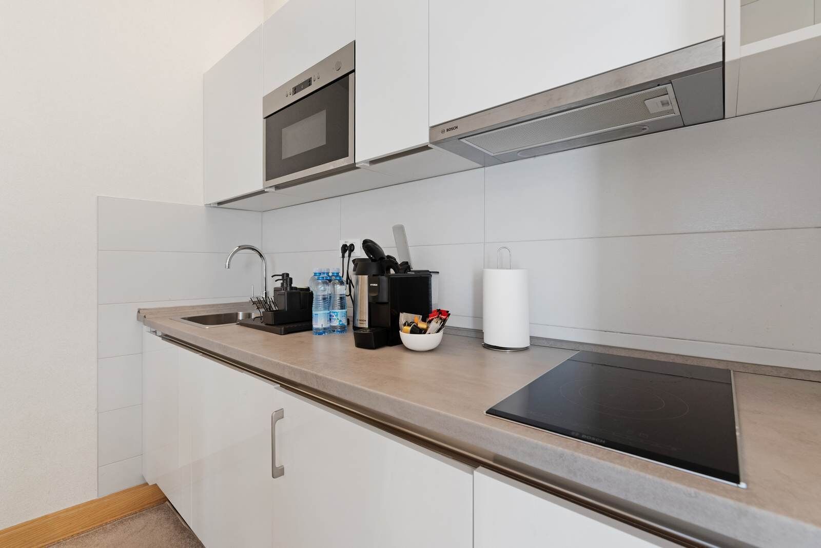 A modern kitchen with a microwave, stove, sink, and various kitchen utensils.