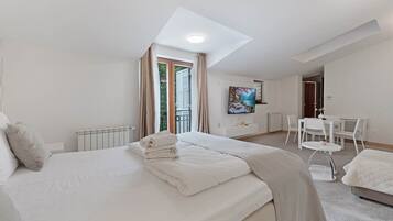 Een moderne hotelkamer met een groot bed, een bureau, een televisie en een balkon met gordijnen.