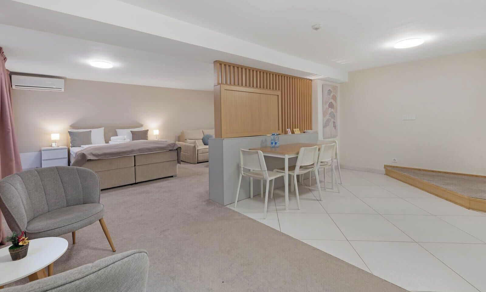A modern hotel room with a bed, a desk, a chair, and a small table.