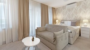 Une chambre d’hôtel avec un lit, un canapé, une petite table et une table de chevet avec des lampes.