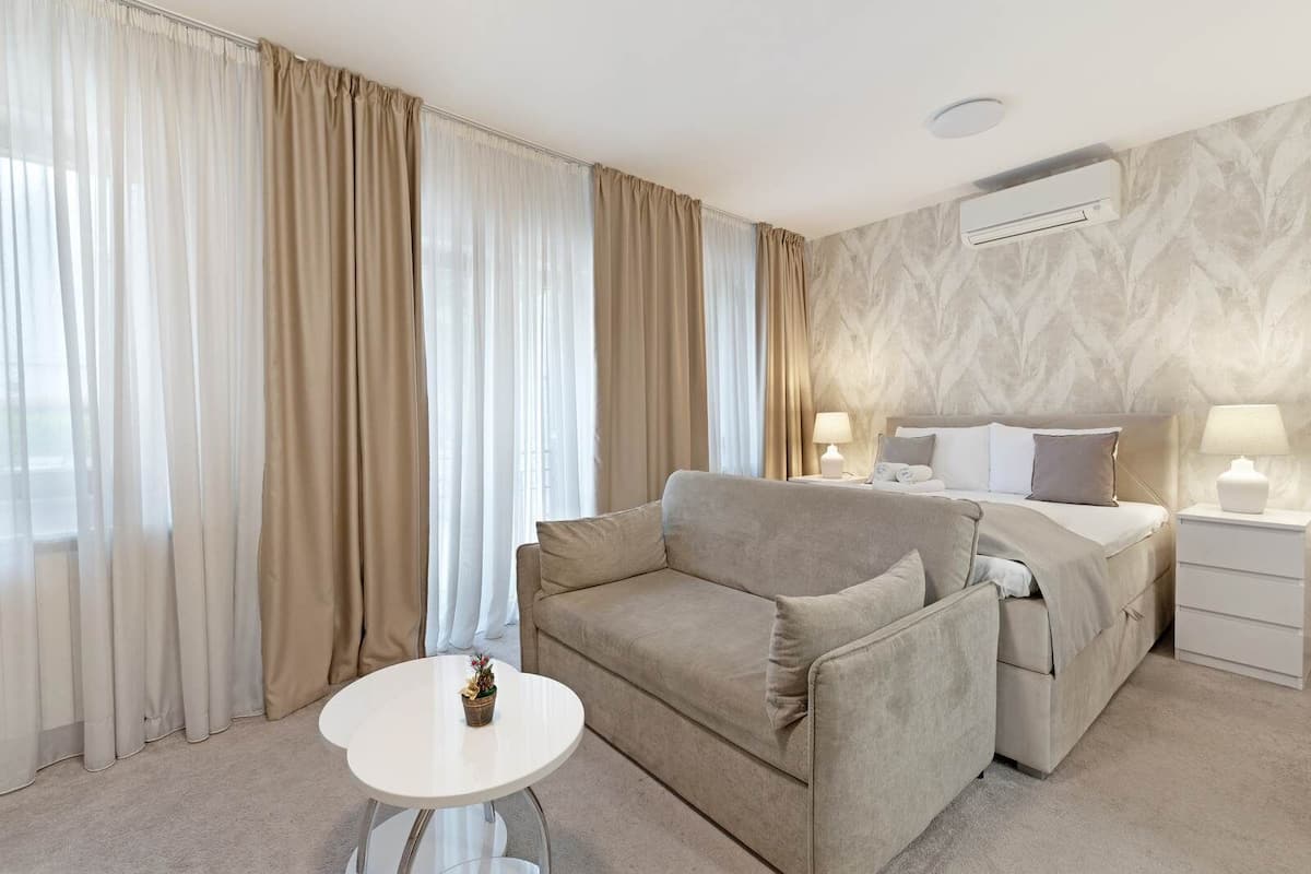 Ein Hotelzimmer mit einem Bett, einer Couch, einem kleinen Tisch und einem Nachttisch mit Lampen.
