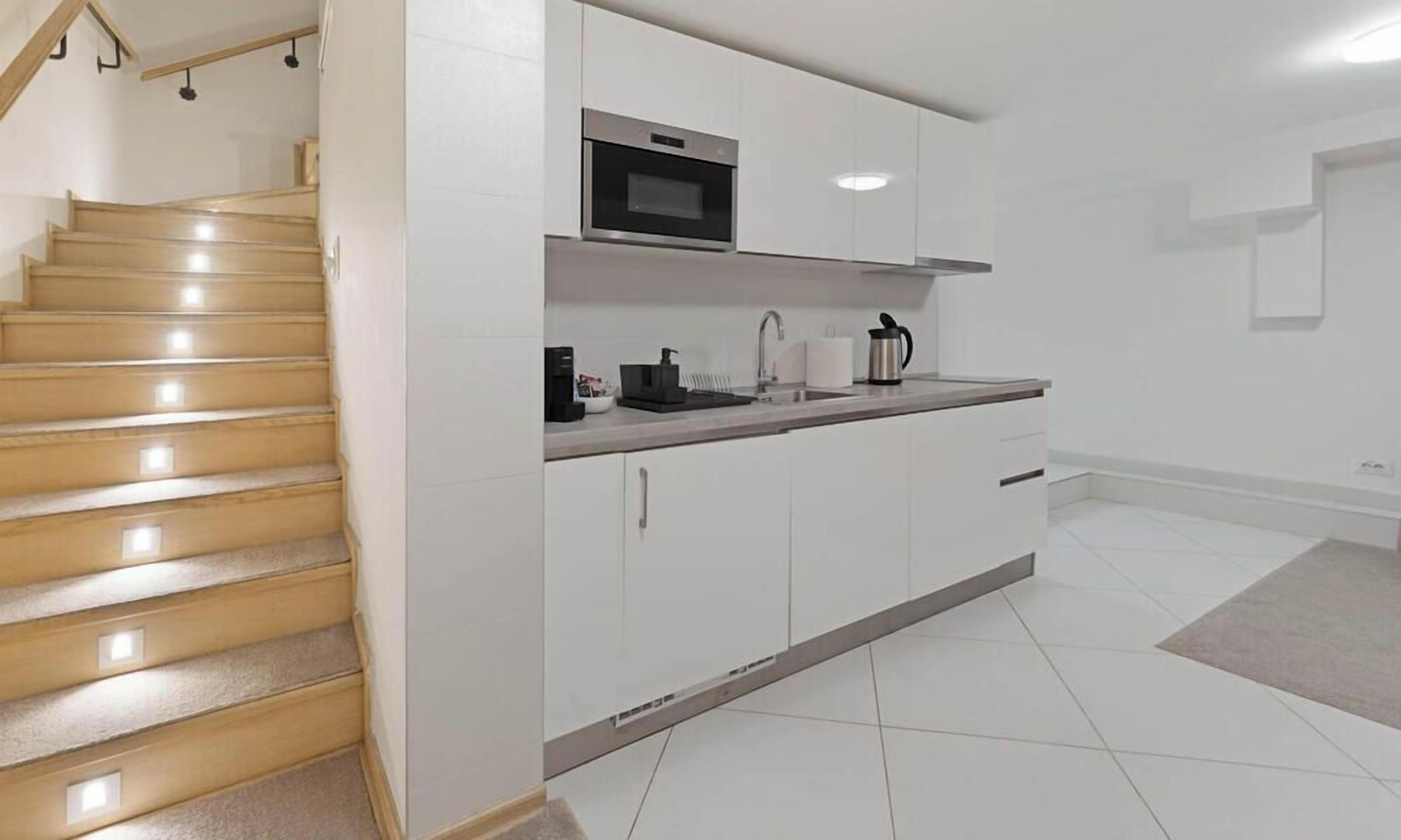Una cocina moderna con armarios blancos, un microondas de acero inoxidable y un horno empotrado.