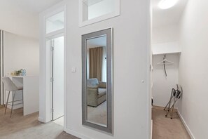 Egy modern szállodai szoba, melyben található egy nagy tükör, egy ülősarok egy székkel, egy kis asztallal és egy kabátállvány.